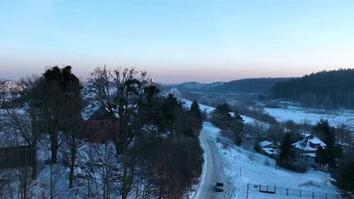 A serene winter scene showcasing a snowcovered landscape a winding road and scattered houses in