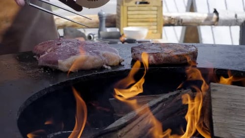 Chef cooking juicy beef steaks on a flaming barbecue grill. Professional cook grilling seasoned