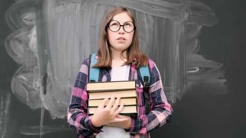 Teenage Student with Books in Front of Chalkboard