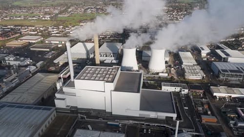 Luftbild eines Kraftwerkskomplexes mit hoch aufragenden Kühlaggregaten und angrenzendem Industriegebiet,