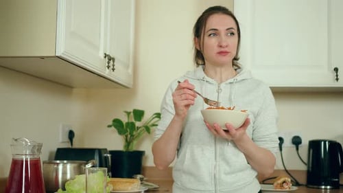 Woman Eating Carrot Salad in Modern White Kitchen Female Enjoying Fresh Vegetable Dish in