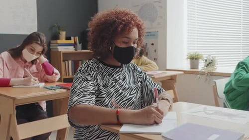 Students Wearing Face Masks Writing at Desks