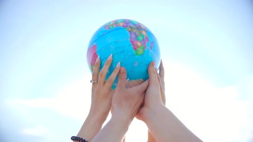 Hands Holding Up an Inflatable Earth Globe