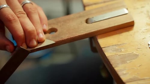 A person uses a woodworking tool to create a metal blade.