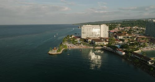 Golden hour dolly across luxury resort with gleaming glass water reflections off the coast of Jamaic