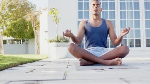 Focused biracial man practicing yoga meditation in sunny garden, slow motion