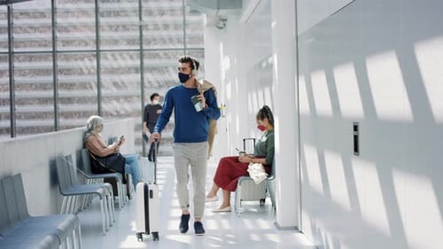 Young man walking to flight gate in airport terminal during coronavirus pandemic
