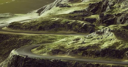 Winding Road Through Lush Hills and Rocky Landscapes at Sunset