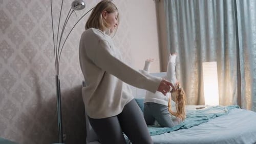 Woman and Little Girl Playfully Dancing in Bedroom