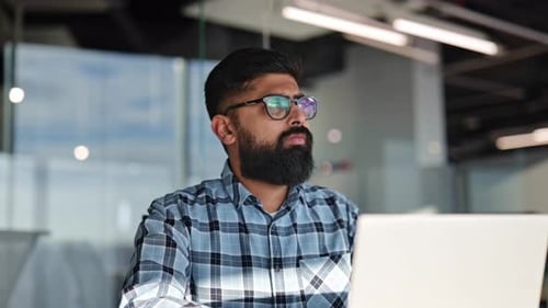 Focused Businessman Working on Laptop in Modern Office