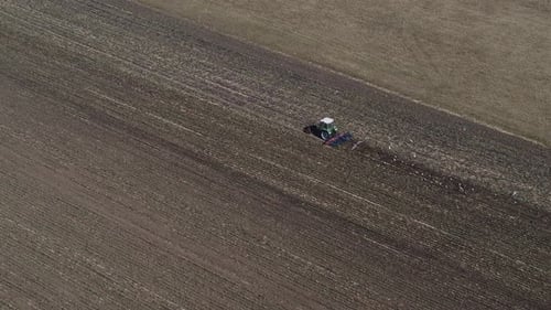 Agriculture Aerial view -Tractor plows field and birds fly after it
