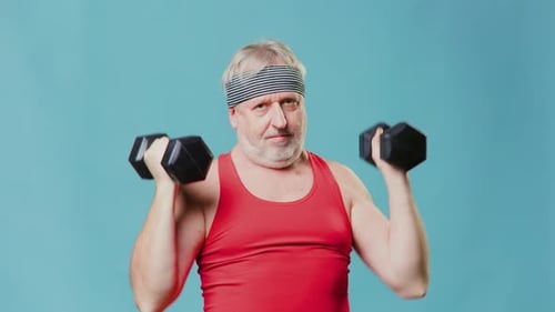 Active Senior Men Showcases Energy with Dumbbells and Studio Background