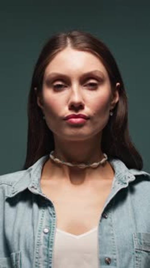 Young Attractive Woman Look on Camera Serious Turns Head on Gray Blue Background Light and Shadow