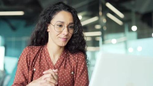 Businessman talking on a video call using a laptop sitting at desk at workplace in business office.
