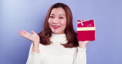 Excited Woman with Birthday Gift on Purple Background