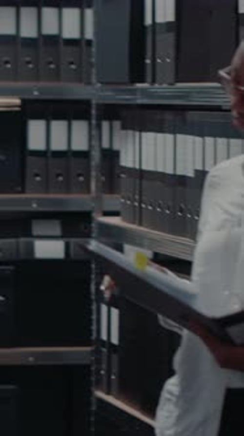 Young Adult Reviews Documents in Dark Office Archive