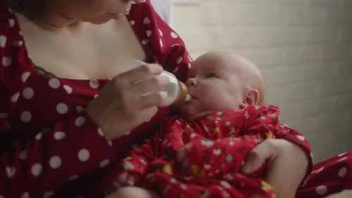 Mother Feeds Baby with Bottle in Home