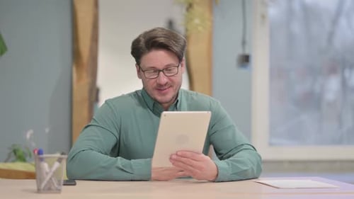 Man Video Calling With Tablet At Desk