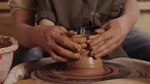 A Man Potter Works in a Workshop Together with Son Uses a Rotating Pottery Wheel to Mold a Small