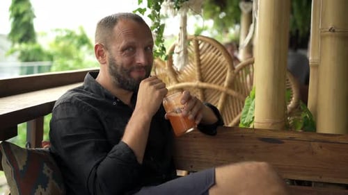 Young, Happy Man Drinking Cocktail Sitting In Cafe