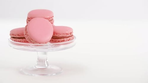 Sweets, Pastry and Food Concept - Pink Macarons on Glass Confectionery Stand