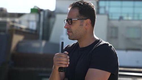 Man Speaking into Walkie-Talkie Outdoors During Daytime
