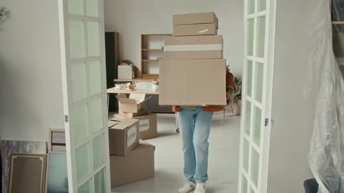 Young Man Carrying Heavy Stack of Moving Boxes