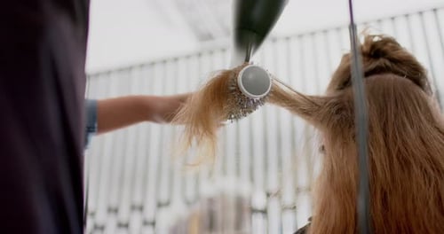 Hair Stylist Blow Drying Client's Golden Hair