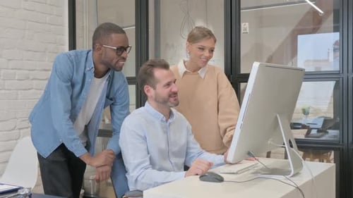 Cheerful Colleagues Collaborating on Computer Project in Office