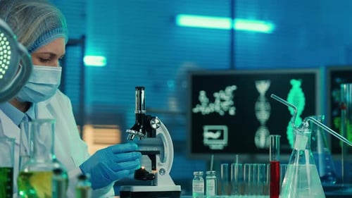 Female Scientist Examining Sample Under Microscope in Laboratory