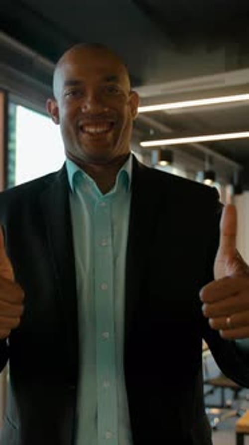 Happy Businessman Giving Two Thumbs Up in Office
