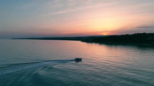 Boat Gliding Across Ocean at Sunset Aerial View