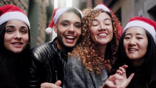 Smiling Friends Wearing Santa Hats Pointing at Camera