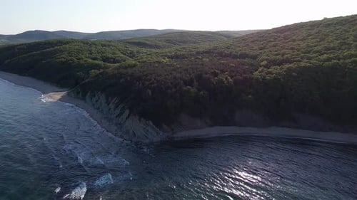 Beach Between a Ledge Covered with Vegetation and a Black Sea Under a Clear Blue Sky