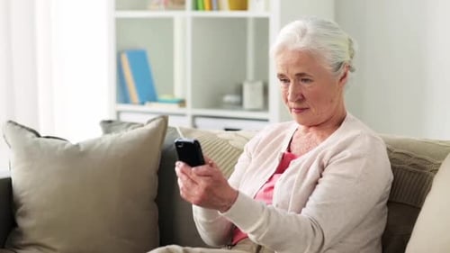 Senior Woman Using Smartphone on Couch Indoors