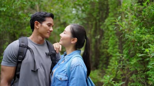 4K Young Asian couple hiking together in tropical forest.