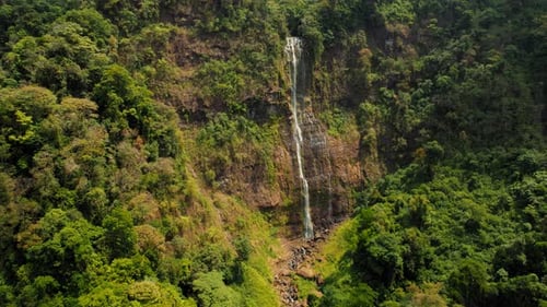 Tall waterfall Catarata Diamante cascading down a lush green cliff in Costa Rica