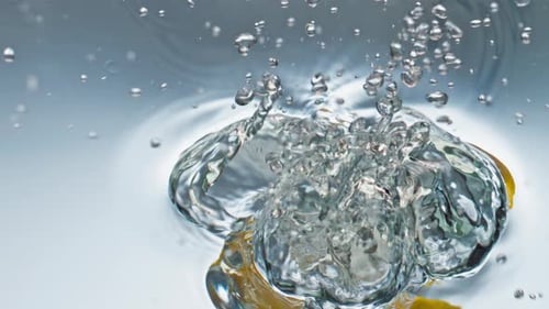 Fresh yellow lemon splashing into clear water