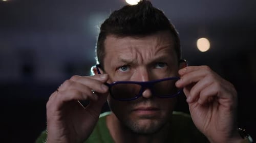 Um homem com óculos posou em um cenário cinematográfico envolvente, chamando a atenção do público
