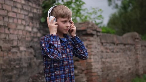 Young Boy Wearing Headphones and Dancing Energetically He's Dressed in a Blue Plaid Shirt and Black