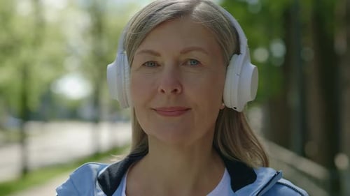 Portrait Senior Sport Woman Wearing Headphones Looking at the Camera Standing Outside
