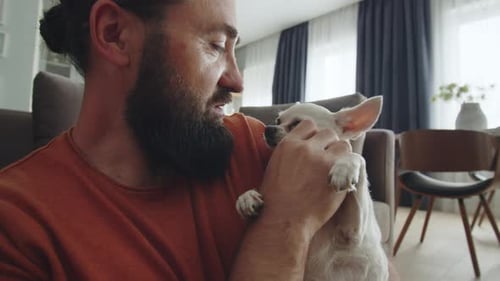 Man Smiling at Small White Dog Indoors