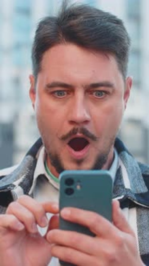 Caucasian Mature Man Looking Shocked While Reading Good News on Smartphone in Downtown City Street