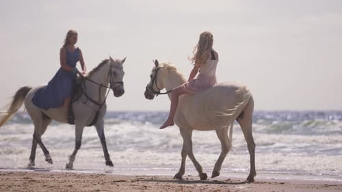 Two Girls Riding Horses By The Beach