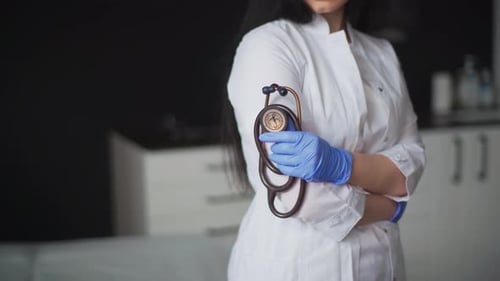 Female Doctor Holding Stethoscope in Medical Setting