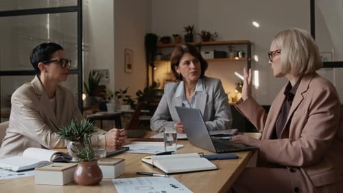 Three Professional Middle-Aged Women Collaboratively Working in Office Workspace