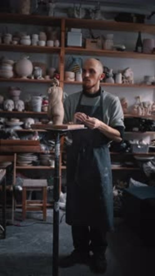 Fulllength Portrait of a Young Bearded Sculptor Molding By Hands a Limestone Figurine in Workshop