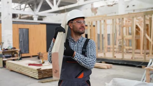 Construction Worker Carries Lumber in Warehouse