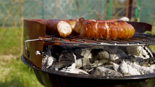 Grilling Delicious Sausages Over The Coal Fire Outdoor On A Sunny Day - close up