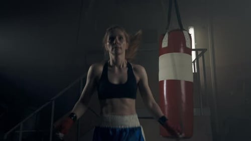 Female Boxer Jumping Rope in Dark Gym